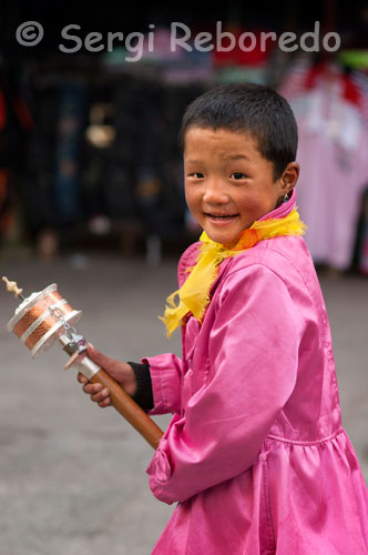 Un niño tibetano hace girar su molino de oración en las calles de Lhasa. Miles de debotos tibetanos hacen girar sus molinillos de oración, a la vez que hacen el Kora alrededor del Kokhang y recitan sus oraciones. En el interior del molinillo se encuentra un papel escrito con la oración que recitan, de forma que cuando lo hacen girar una vez, es como si recitaran la oración. 