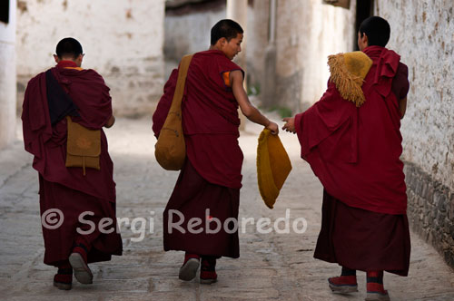 Monjes en el interior del Monasterio Tashilumpo, ubicado en Shigatse, Tibet.  Además de perderse por las callejuelas e innumerables capillas de Tashilumpo, el buen viajero no debe olvidarse de recorrer su lingkor (ruta de peregrinación). En esta senda de tres kilómetros que circunvala al monasterio circulan numerosos devotos que giran las omnipresentes ruedas de plegarias mientras entonan el sagrado “om”. Este mantra, uno de los más sagrados del budismo, está compuesto en sánscrito de tres letras: A, U y M. Cada una de ellas representa un estado de conciencia: A simboliza el estado de vigilia; U, el estado de ensueño, y M, el estado de sueño profundo.