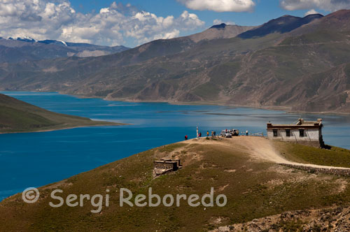 Lago Yamdrok visto desde el paso de Kamba La. El lago se encuentra a unos 90 km al oeste de la ciudad tibetana de (unos 60.000 habitantes en 2003) y a unos 100 km al noreste de la capital.  El lago, de profundidad desconocida, tiene forma de abanico, que se abre hacia el sur y apenas hacia el norte. El orilla del lago es montañosa, muy almenada, con numerosas bahías y ensenadas. El lago Yamdrok se congela en invierno. El lago Yamdrok tiene una central eléctrica que fue terminada y puesta en funcionamiento en 1996, cerca del pequeño pueblo de Pai-Ti en el extremo occidental del lago. Esta central es la más grande en el Tíbet.