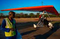Microlight flights over Victoria Falls. Airstrip and pilots. Viewing the majestic Victoria Falls from above in an open cockpit with the wind in your hair and the sun in your face is an awe-inspiring experience. A microlight flight over the Falls is truly an adventure like no other. It can't be explained. It must be experienced! The "weight-shift" microlights carry a pilot and one passenger. Unfortunately, you won't be allowed to bring your camera, but the Microlights have a unique wing-mounted camera so you'll still be able to take home some amazing pictures in the microlight with the beautiful scenery of the Falls behind you (available for seperate purchase). The 12-15 minute microlight flips ($160) offer an outstanding photographic opportunity to view the full breadth of Victoria Falls, the islands and neighbouring rainforests.  Spray blasts out of the chasm as the full volume of the Zambezi crashes down 108 metres.  