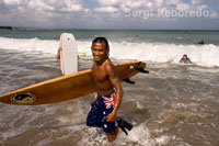 A surfer with his board on the beach of Kuta. Bali.