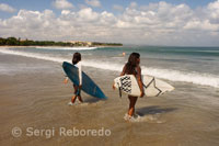 Two female surfers with their boards on the beach of Kuta. Bali.