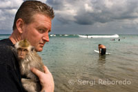 A tourist with a monkey on the beach of Kuta. Bali.