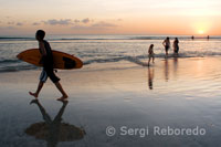 A surfer takes his table at sunset on the beach of Kuta. Bali. Indonesia.