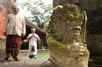 Several people close to a Hindu statue in the stone gate of the Temple Pura Gunung Lebah. Ubud. Bali.
