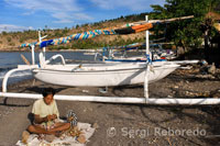 A fisherman, along with several fishing boats on the beach in Amed, a fishing village in East Bali.