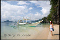 A tourist in Cudugman Cave next to a bank, the typical Philippine boat. Palawan.